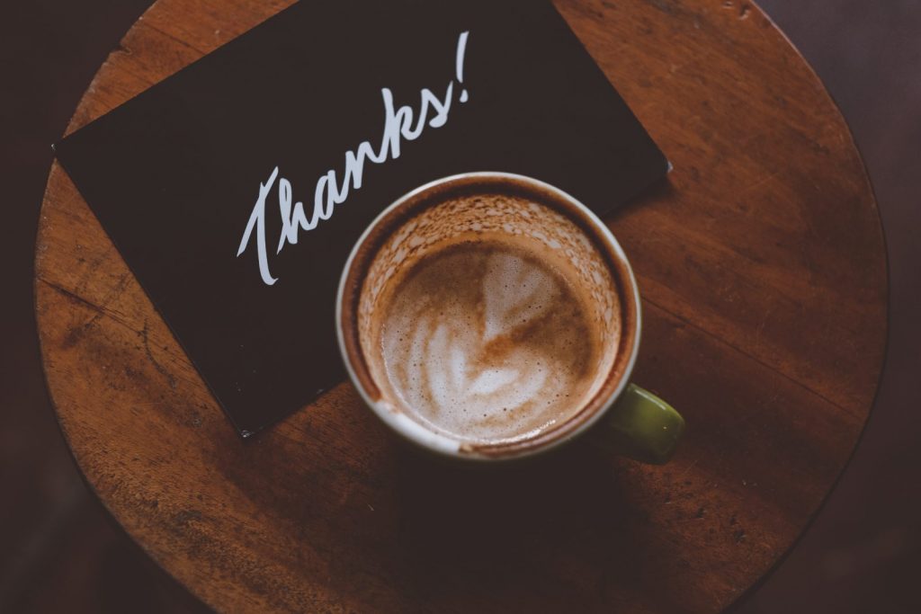 A coffee and a thank you card on a table.