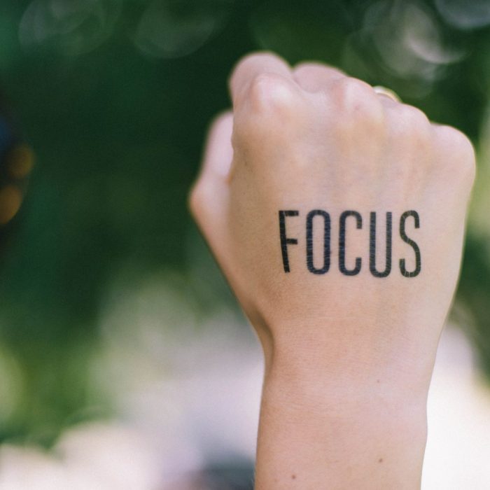 The word "focus" written on the back of someone's fist, with the background blurred.