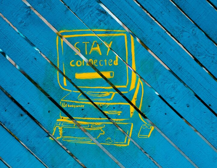 A drawing of a yellow computer with an old CRT monitor that says Stay Connected, on a blue wooden sign.